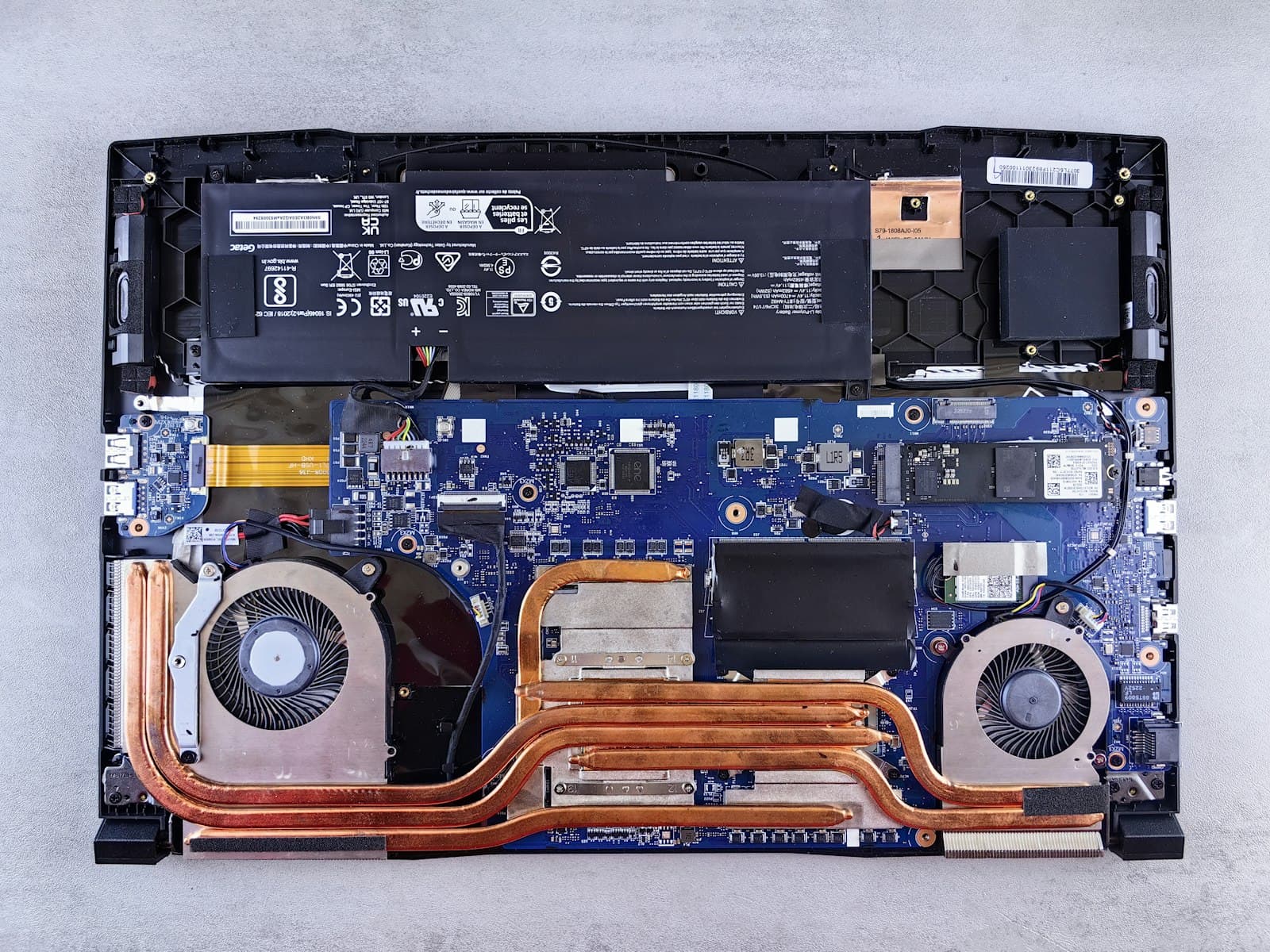 Opened laptop showing mainboard, battery and cooling